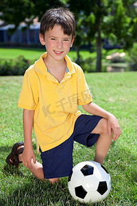 一个小男孩在外面踢足球或足球跪在草地上的阴影的目标