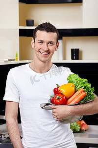 厨房里端着一碗蔬菜的年轻人