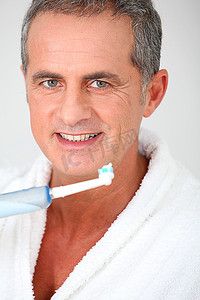 使用电动牙刷的成熟男子肖像