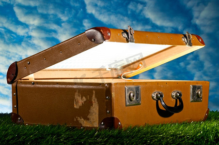 从草地上的旧行李箱里照亮，旅行的概念