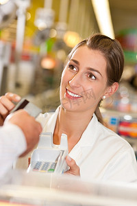 超市收银台摄影照片_超市里的一名男性顾客把信用卡交给收银台的收银员，以便付款