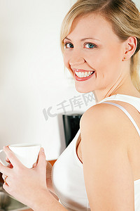 美丽的女人显然享受一杯热咖啡在早上