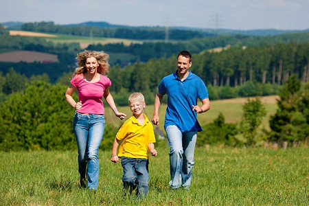 阳光明媚的夏日，年轻的一家人在草地上奔跑，享受着阳光的乐趣