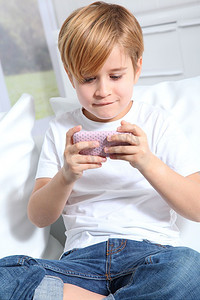 手机常用应用图标摄影照片_金发小男孩玩电子游戏的肖像