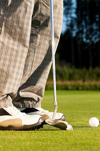高尔夫球手将球打入洞内，只能看到脚和铁头