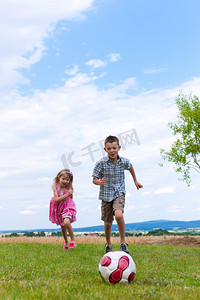 兄弟姐妹--儿子和女儿--在花园里踢足球