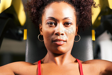 非常健康和美丽的非裔美国女性在健身房里锻炼，在健身器上举重
