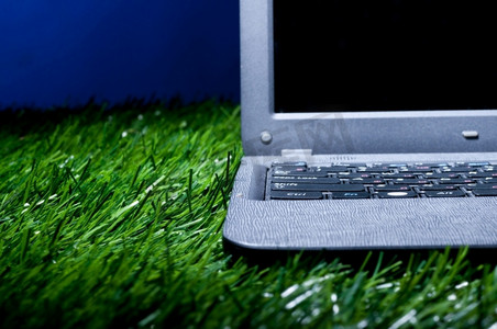 草地上的现代笔记本电脑在黑暗中照亮