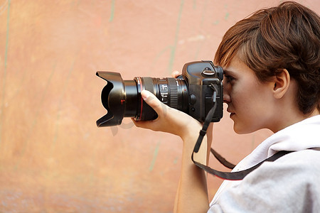 女摄影师配备专业单反相机，自然光，选择性对准眼睛