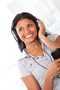美丽的拉丁女孩戴着耳机听音乐