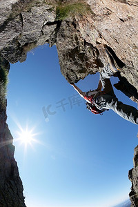 登山路线的绝佳视角：年轻人攀登岩石山脊，背光，鱼眼镜头，垂直框架。