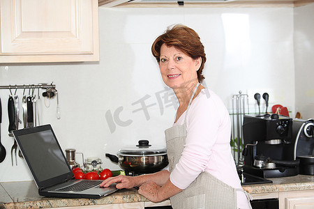 厨房里拿着笔记本电脑的高级女性特写