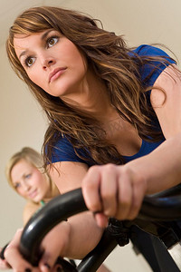 健身房里一位年轻漂亮的黑发女子骑着健身车/旋转自行车