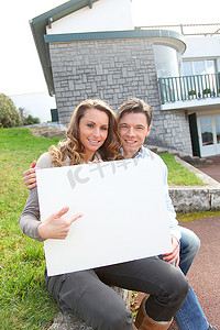 购房者摄影照片_一对夫妇在家门口举着白板