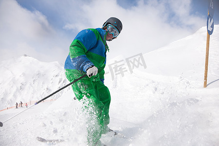 滑雪道上的一名男子正在下坡，在镜头前停下来撒了一些雪