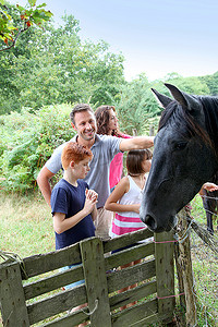 父母和孩子在农村抚摸马匹