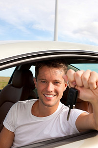 开心驾驶摄影照片_一名男子拿着车钥匙坐在车里，显然玩得很开心