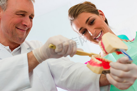 牙科教学摄影照片_牙医用假牙向病人解释刷牙
