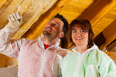 一对夫妇在屋顶上用玻璃棉安装隔热材料，他们看起来相当自豪