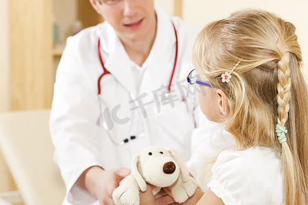 感谢有你相随摄影照片_医生--儿科医生--和他诊所里的一位儿童病人在一起，她正用她的柔软玩具来感谢他。