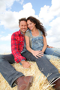 大包摄影照片_幸福的夫妇坐在农田里的大包上