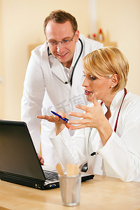 两名医生--男性和女性--讨论笔记本电脑屏幕上显示的测试报告