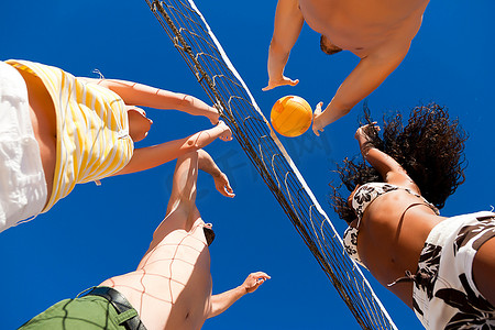 在沙滩排球比赛中，参加夏季运动的球员试图阻挡危险的进攻