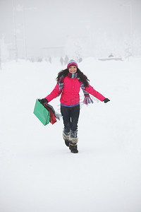 游戏礼包盒摄影照片_雪地上拿着礼包的冬日女孩