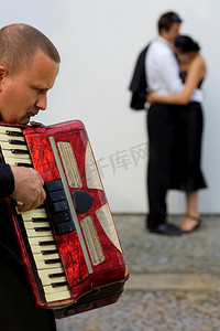 拉丁文摄影照片_街头音乐家用手风琴为两对年轻恋人唱小夜曲