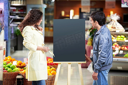 木板牌子摄影照片_那男的和那女的看着商店里的一个空牌子