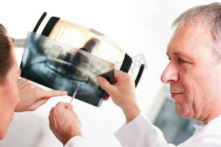 牙医向他的病人解释X光照片的细节，专注于医生的眼睛