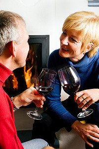 一对成熟夫妇在浪漫的环境中用红酒碰杯，玩得很开心