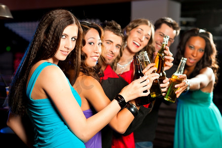 一群人在酒吧或俱乐部里喝着鸡尾酒玩得很开心；一名女子正盯着镜头