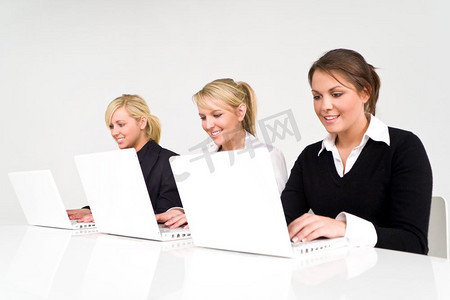 一个由三名女商人组成的团队在现代干净清新的环境中使用白色笔记本电脑，重点放在中间的高管身上。