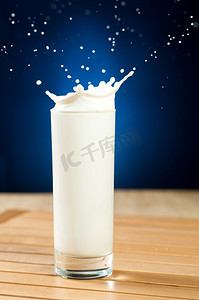 牛奶溅在木桌上的玻璃杯里