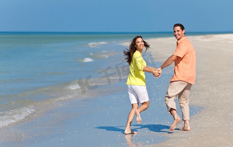 情侣牵着手摄影照片_幸福的情侣牵着手在海滩上奔跑