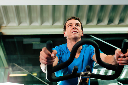 男人在健身房里旋转，锻炼双腿，骑自行车进行有氧训练
