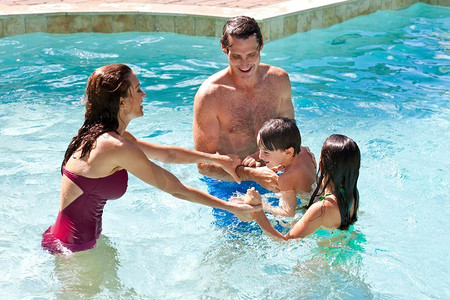 一对父母在假期里和孩子们在游泳池里玩得很开心