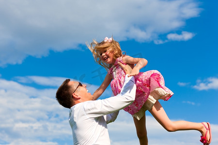 家庭事务-父亲和女儿在夏天玩耍；他把她扔到空中
