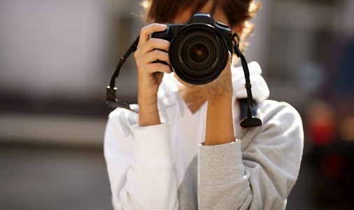 女摄影师配备专业单反相机，自然光，选择性对焦最近的镜头与融合