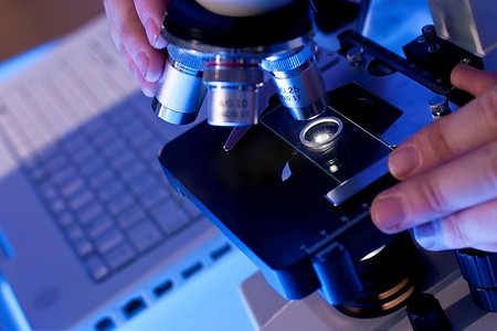 使用显微镜和笔记本电脑的医学或科学研究人员