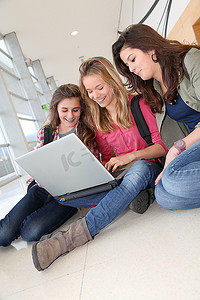 一群十几岁的女孩在学校里拿着笔记本电脑