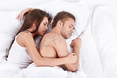 入睡摄影照片_年轻夫妇在床上拥抱入睡