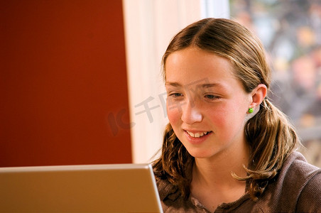 小女孩在家里用无线笔记本电脑做作业。
