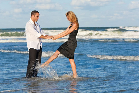 一对年轻的男女在蔚蓝的海滩上作为浪漫的情侣在快乐地跳舞