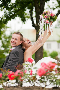看得见的幸福摄影照片_看得见幸福的新婚夫妇坐在公园里有很多玫瑰在前景 