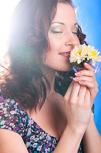 取悦摄影照片_美丽的女人在蓝色背景上用鲜花取悦