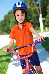 一个戴着头盔、骑着自行车的小男孩