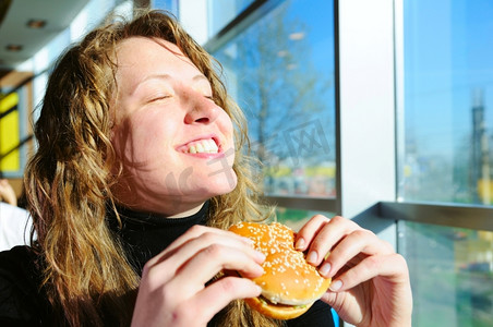 非常开心的女人正在吃芝士汉堡