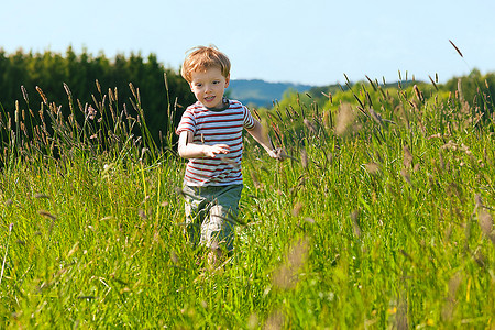 夏天，小男孩在一片美丽的草地上奔跑，场面非常轻松愉快